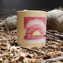 Load image into Gallery viewer, Candle with a pink label on a natural setting with rocks and wood.
